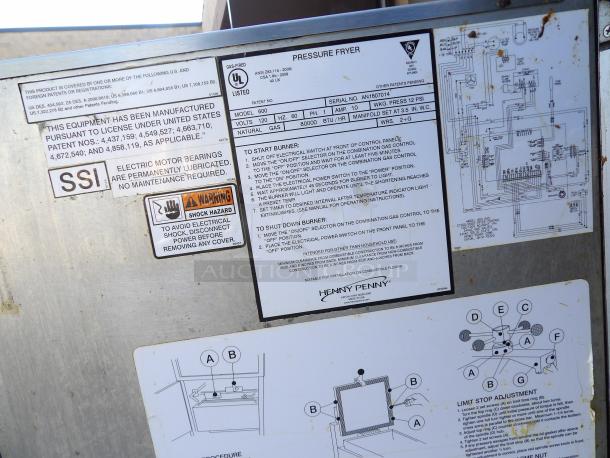 Henny Penny 600 stainless steel pressure fryer, natural gas-powered, on commercial casters. Visible instructions and safety labels.
