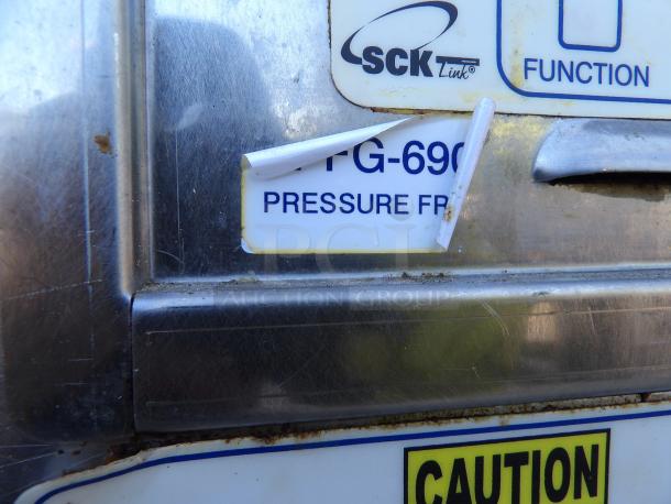 Henny Penny PFG-690 stainless steel pressure fryer, gas-powered, 100,000 BTU, with filtration system. Visible labels and wear.