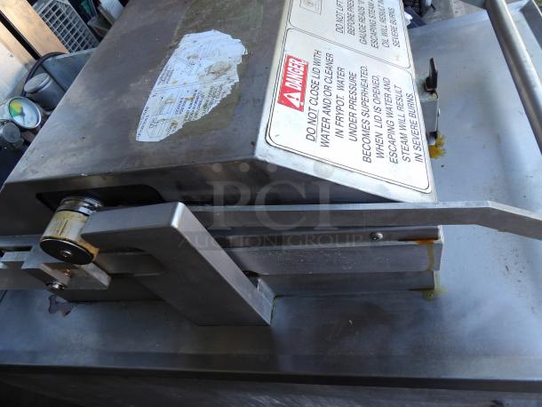 Henny Penny PFG-690 stainless steel pressure fryer with filtration system, commercial casters; visible warning label on lid.