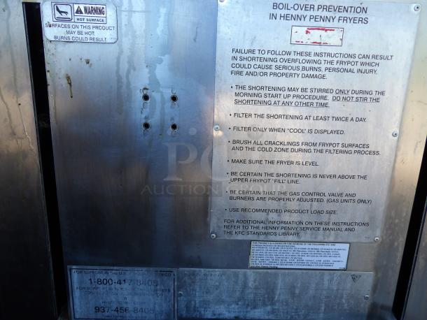 Henny Penny PFG-690 stainless steel pressure fryer, featuring a filtration system, warning labels, and operational instructions.