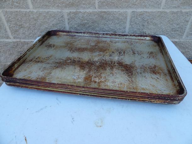 Five full commercial size metal pans, used condition, visible scratches and discoloration, stack on table.