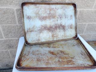 Set of 5 full commercial-size metal pans, well-used with visible scratches and discoloration, likely for heavy-duty baking.