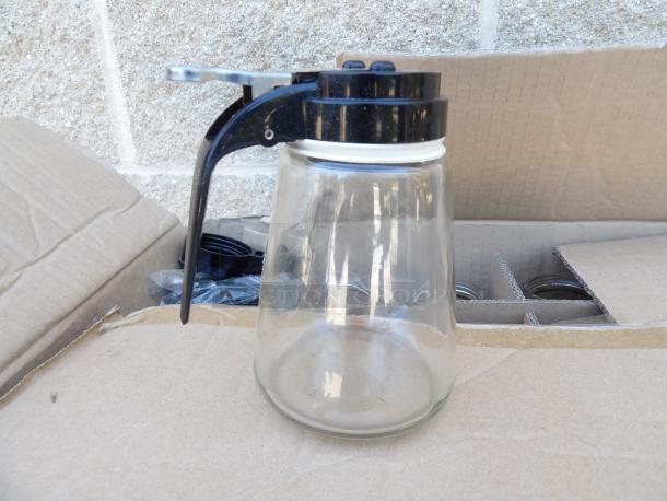 Modern 12oz glass syrup dispenser with black plastic lid and lever, new condition. Auction lot includes multiple units.