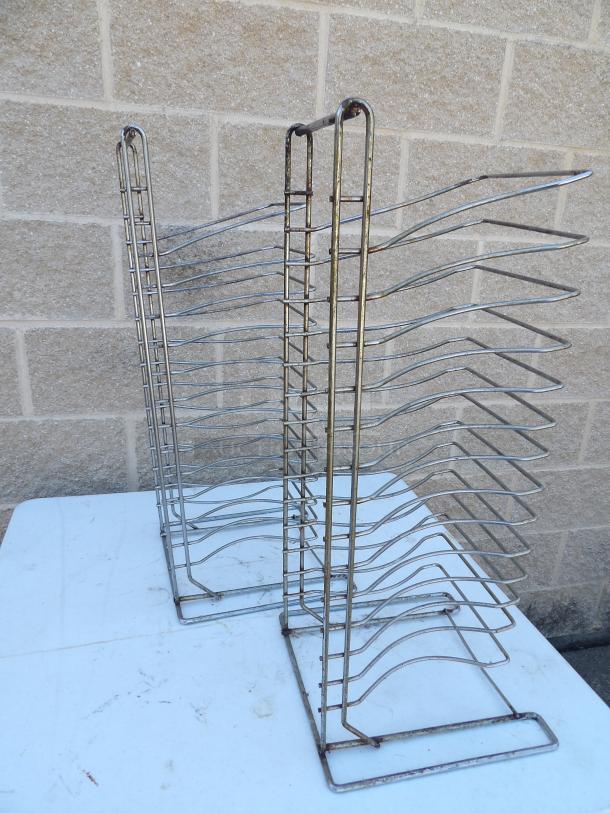 Metal pizza pan racks for auction, featuring multiple slots for pan storage. Visible wear, suitable for restaurant use.