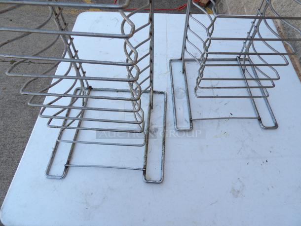 Metal pizza pan racks, used condition, with visible wear, designed to hold multiple pans vertically.