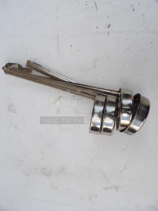 Set of four 6-ounce stainless steel ladles, used condition, stacked together, suitable for liquid serving in kitchens.