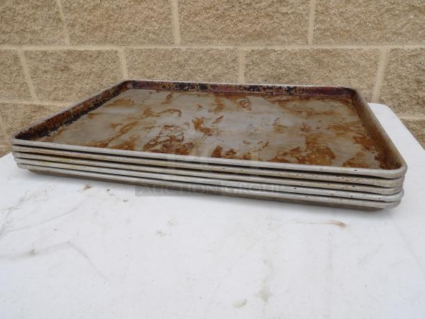 Full size sheet pans, set of five, used condition with visible wear and discoloration, metal construction.