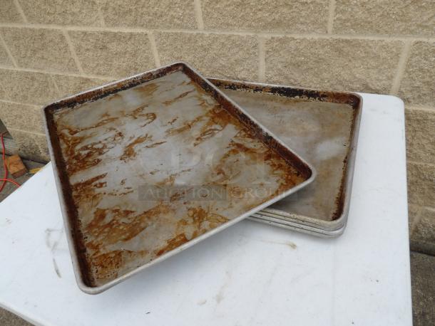 Two full-size sheet pans with visible wear and patina, suitable for baking or roasting. Auction offers 5 times your bid.