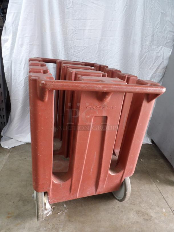 Cambro dish dolly caddy on wheels, red plastic, used condition, features multiple slots for dishes, embossed "Cambro" logo.