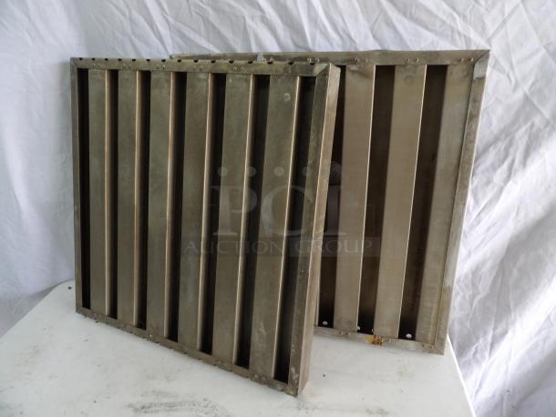 Two metal grease filters, measuring 19.5x20x1.5 inches, showing signs of wear, with visible rivets and slats.