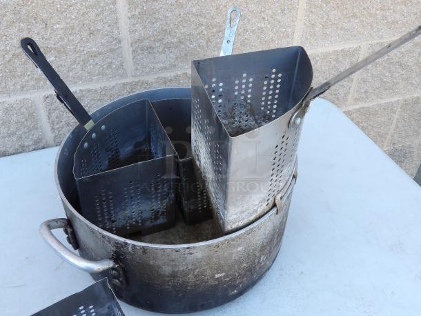 Aluminum pot with four removable strainers, 14" round x 7-1/2" deep, used condition, visible handles, and drain holes.