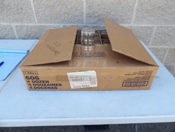 Libbey Glassware 12oz, box of 48 glasses. Box labeled "606, 4 Dozen." Cardboard box with partial lid open, glasses visible.