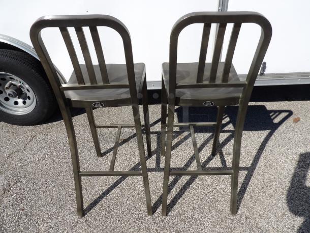 Pair of industrial aluminum bar stools with slatted backs. Each features a label with "USS" text. Excellent condition.