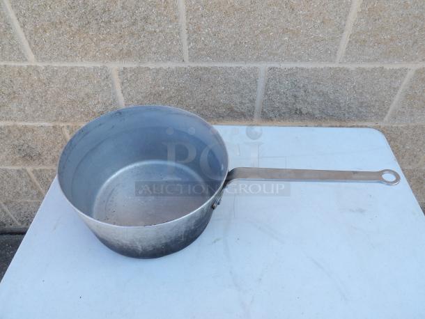 10 Qt. tapered aluminum saucepan with long handle, showing signs of wear, suitable for large batch cooking.