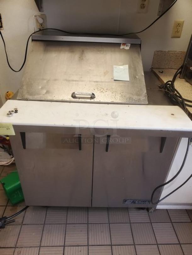 True TSSU-36-12M-B Mega-Top Solid Door Sandwich/Salad Unit, stainless steel, visible wear, front handle and True brand logo.