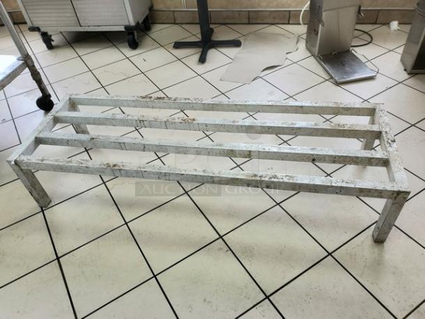 Aluminum dunnage rack on tiled floor, showing a sturdy frame with three support bars. Signs of moderate wear.