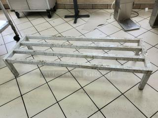 Aluminum dunnage rack on tiled floor, showing a sturdy frame with three support bars. Signs of moderate wear.