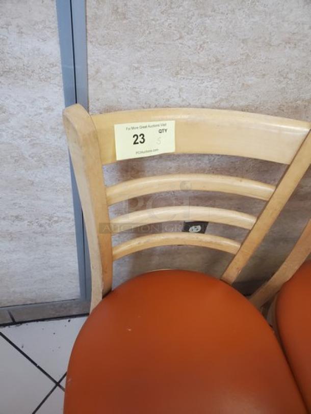 Lot of 5 wooden chairs with ladder-back design and orange seats. Auction tag reads "23 QTY 5," indicating set quantity.