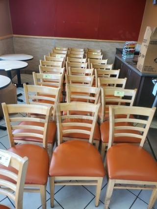 Lot of 5 wooden chairs with orange cushioned seats, ladder-back design. Good condition. Ideal for dining or café use.