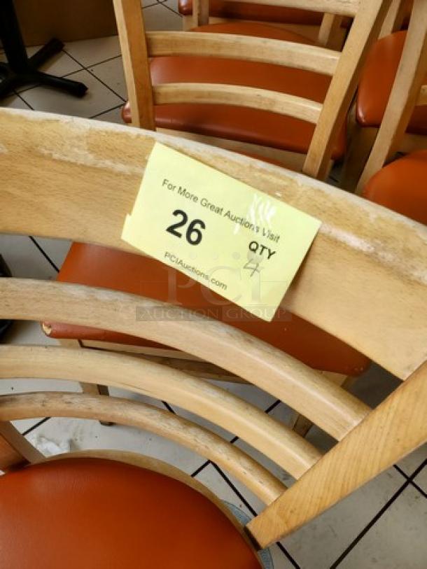 Lot of 4 wooden chairs with orange cushions, curved backrest design. Yellow tag: "26 QTY 4," from PCIAuctions.com.