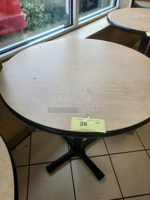 Lot of 2 round table tops with black bases, light wood finish, some surface wear. Auction tag reads "28 QTY 2XBID."