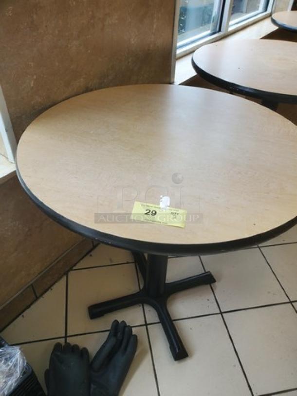 Lot of 2 round table tops with black bases, light wood finish, used condition, visible price tag labeled "29".