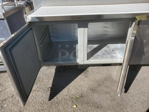 Randell Sandwich Prep Table, stainless steel with open double doors, showing interior storage space, in used condition.