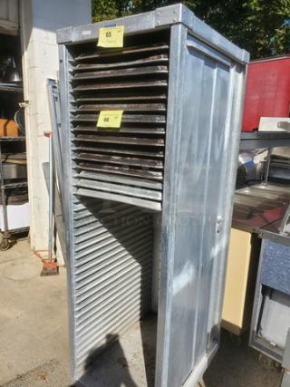 Mobile sheet pan rack, metal construction, used condition. No sheet pans included. Visible labels: "65" and "66."