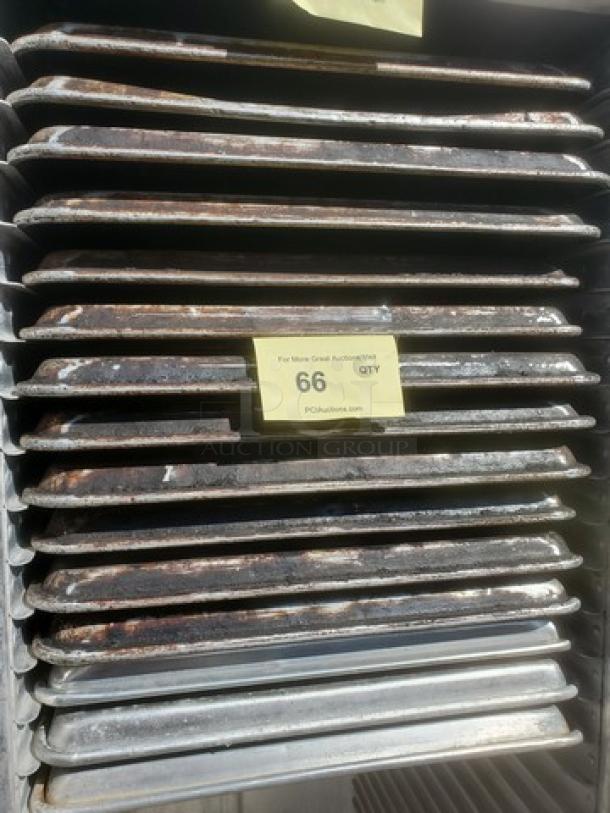 Lot of 15 used sheet pans with visible signs of wear, stacked vertically; auction label shows quantity 66.