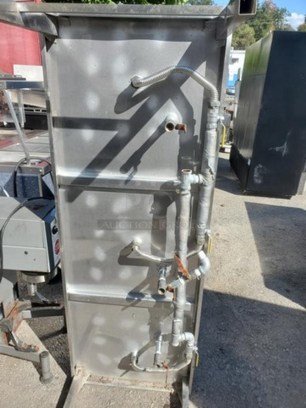 Industrial metal equipment unit with visible pipes and fittings, used condition. No visible branding or labels.