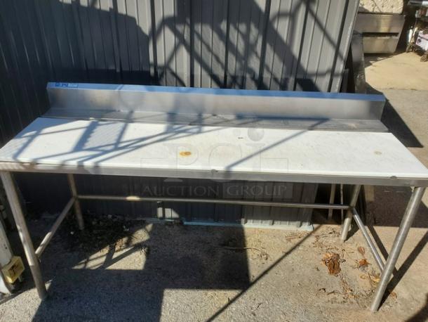 Stainless steel work counter with backsplash, showing minor surface rust stains. Durable construction, ideal for kitchens.
