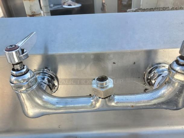 3 Compartment stainless steel sink with dual handle faucet, slightly worn surface. Ideal for commercial kitchens.