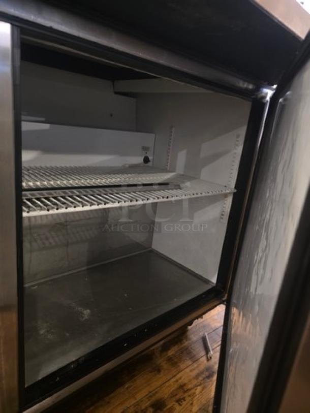 True QA-60-24M-B 60" refrigerated prep table interior with shelving, stainless steel, 115V, showing slight wear.