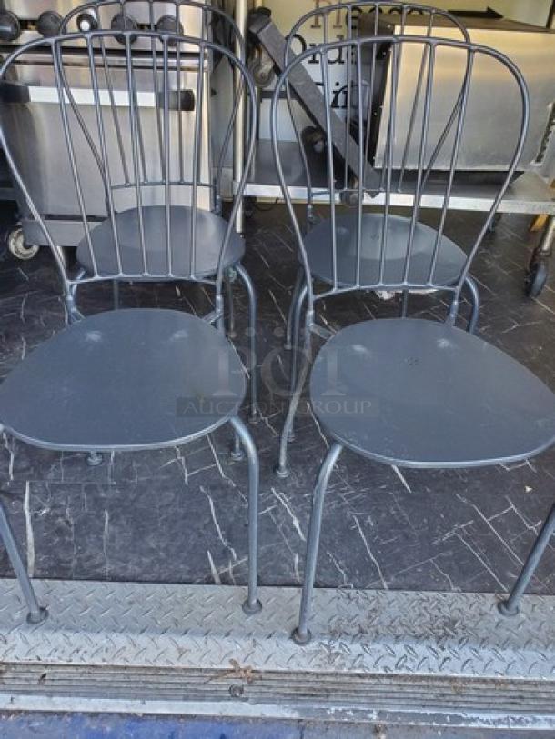 Lot of 4 black metal patio chairs with curved backs and round seats. Minimal wear, durable finish, suitable for outdoor use.