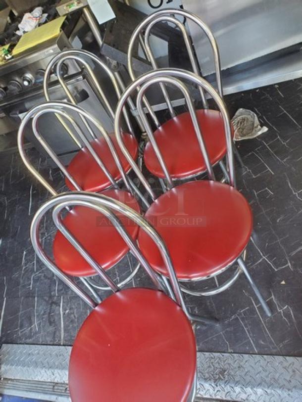 Lot of 4 red cushioned dining chairs with silver metal frames. Features curved backrests. Good condition.