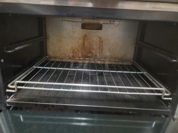 Interior of an American Range 6 Burner Natural Gas Range showing an oven rack. Used condition with visible signs of wear.