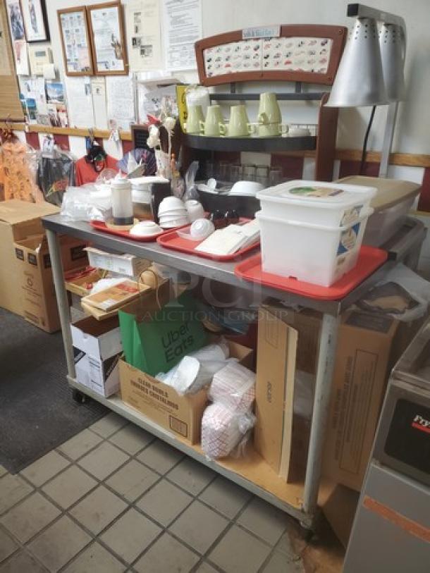 Stainless steel table with undershelf on casters; used condition. Contents not included. Ideal for kitchen or storage use.