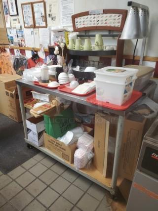 Stainless steel table with undershelf on casters; used condition. Contents not included. Ideal for kitchen or storage use.