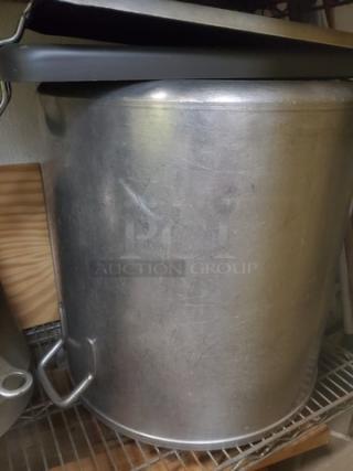Large metal pot with lid, showing visible wear and scratches. Handles on sides for easy lifting. Ideal for cooking or brewing.
