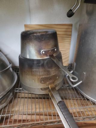 Set of 3 well-used saucepans with metal handles. Stacked on a wire shelf, showing visible wear and discoloration.