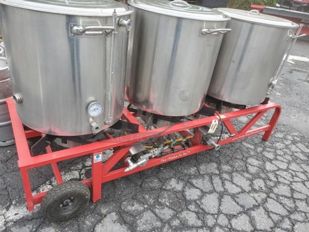 The Alpha Ruby 1 Barrel Brew System with 3 stainless steel kettles on a red wheeled frame. Gas or propane compatible. Includes 8 kegs.