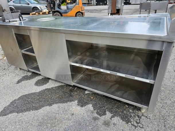 Custom stainless steel work counter/warmer with open shelving, durable surface, and integrated warmer. Slight wear visible.