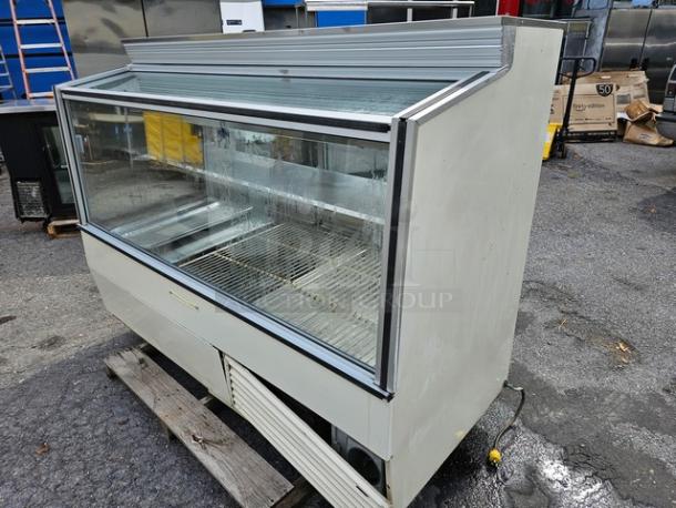 Hussmann SCD-6 refrigerated display case, glass front, off-white exterior, double shelving, visible wear, ideal for retail use.