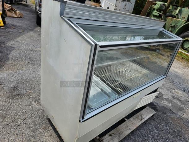 Hussmann SCD-6 refrigerated display case with glass front, metal frame, and shelving, showing signs of wear.