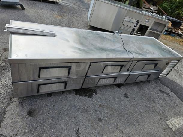 True TRCB-110 six-drawer refrigerated chef base, 110". Stainless steel, showing signs of use. Sturdy and spacious storage unit.