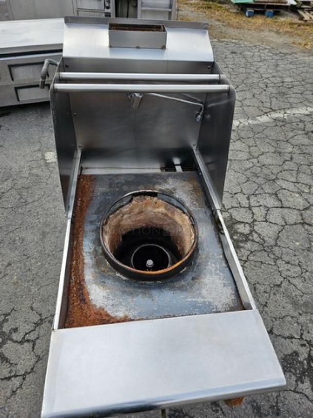 Single burner natural gas wok range with stainless steel body, visible rust and wear around burner, outdoor location.