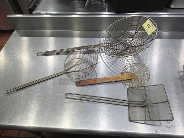 Lot of 4 metal wire skimmers with varied designs and sizes on stainless steel surface; one has a wooden handle.