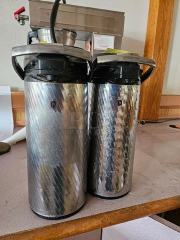 Two Newco Thermal Airpots, silver with black lids, textured design, used condition, ideal for coffee service.