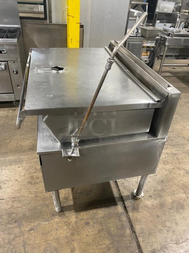 Commercial stainless steel electric braising pan with tilt feature, swivel faucet, on sturdy legs. Ideal for large-scale cooking.