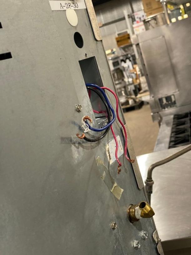 Ice-O-Matic ice machine front panel with exposed wires, model CIM1446HR4/VRC2061B1. Industrial setting in background.